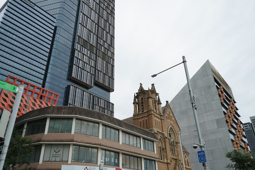 an old church being towered over by large skyscrapers
