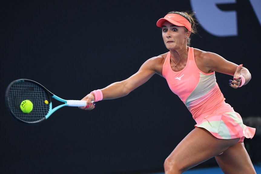 A female tennis player wearing pink reaches for a ball with her racquet.
