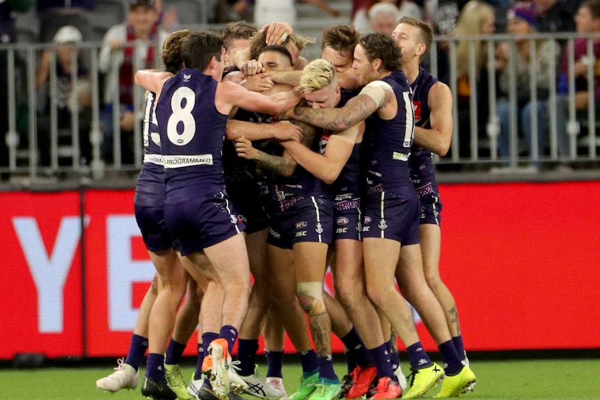 The Dockers at Perth Stadium hugging each other after a game.