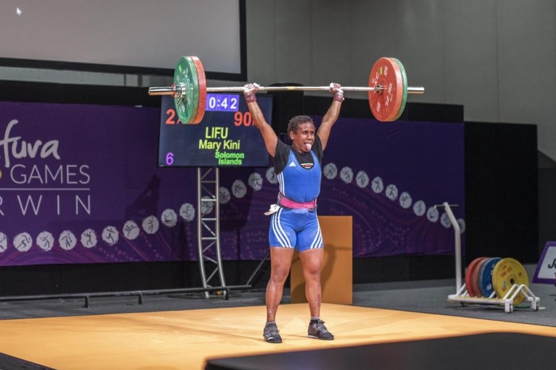 A woman lifts weights in an auditorium.