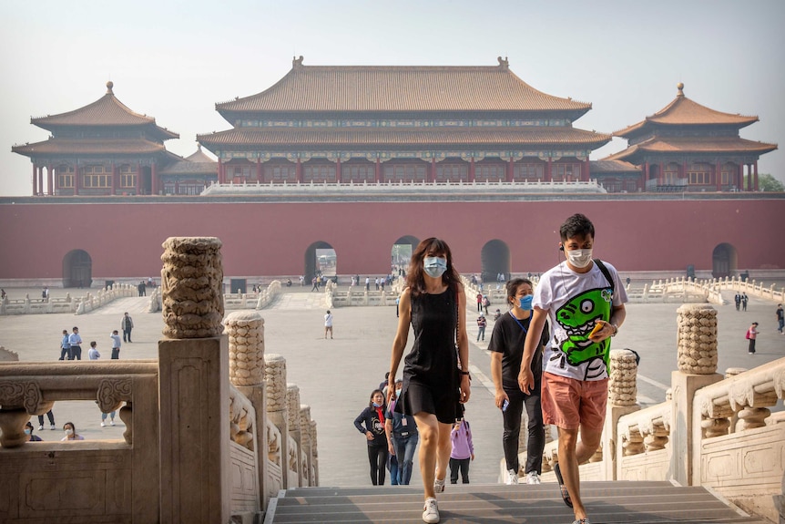 Visitors wearing face masks to protect against the new coronavirus walk through the Forbidden City.