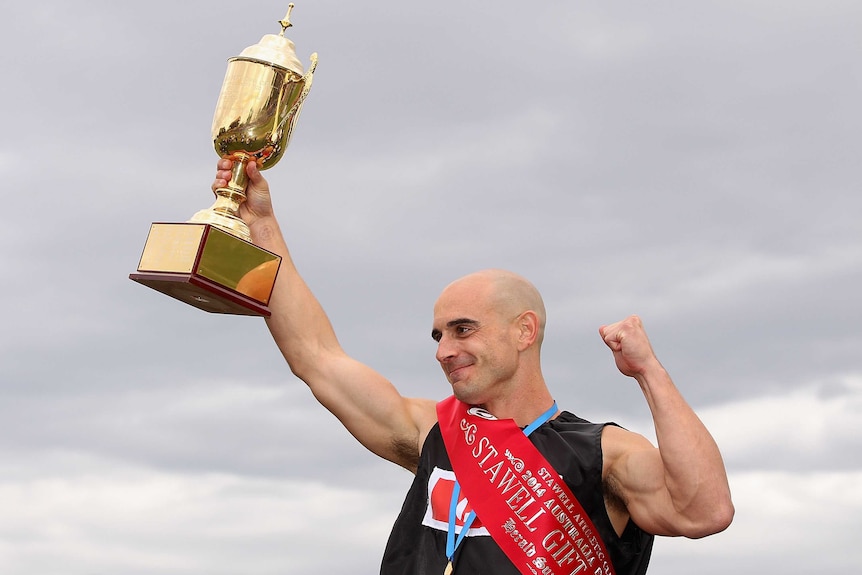 Luke Versace celebrates with the trophy after winning the Stawell Gift at Central Park in Stawell.