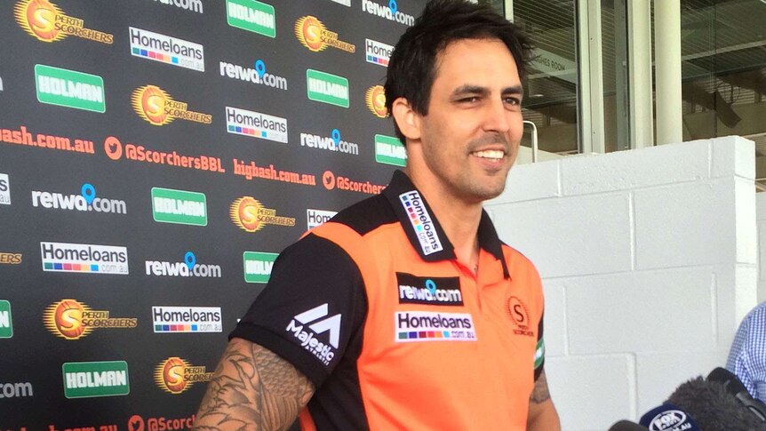 Mitchell Johnson, wearing a Perth Scorchers shirt, standing in front of sponsorship signage.