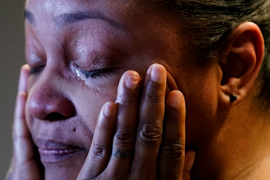 Woman crying while holding her hands to her face.