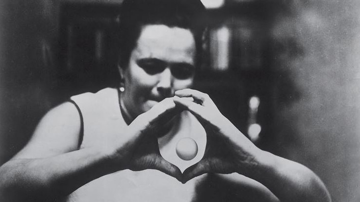 A woman holds her hands together in front of her in a circle, while a ping-pong shaped ball floats in between them.