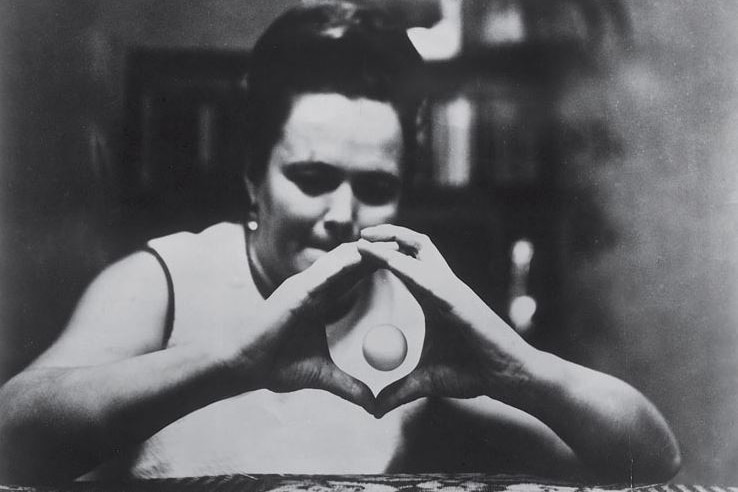 A woman holds her hands together in front of her in a circle, while a ping-pong shaped ball floats in between them.