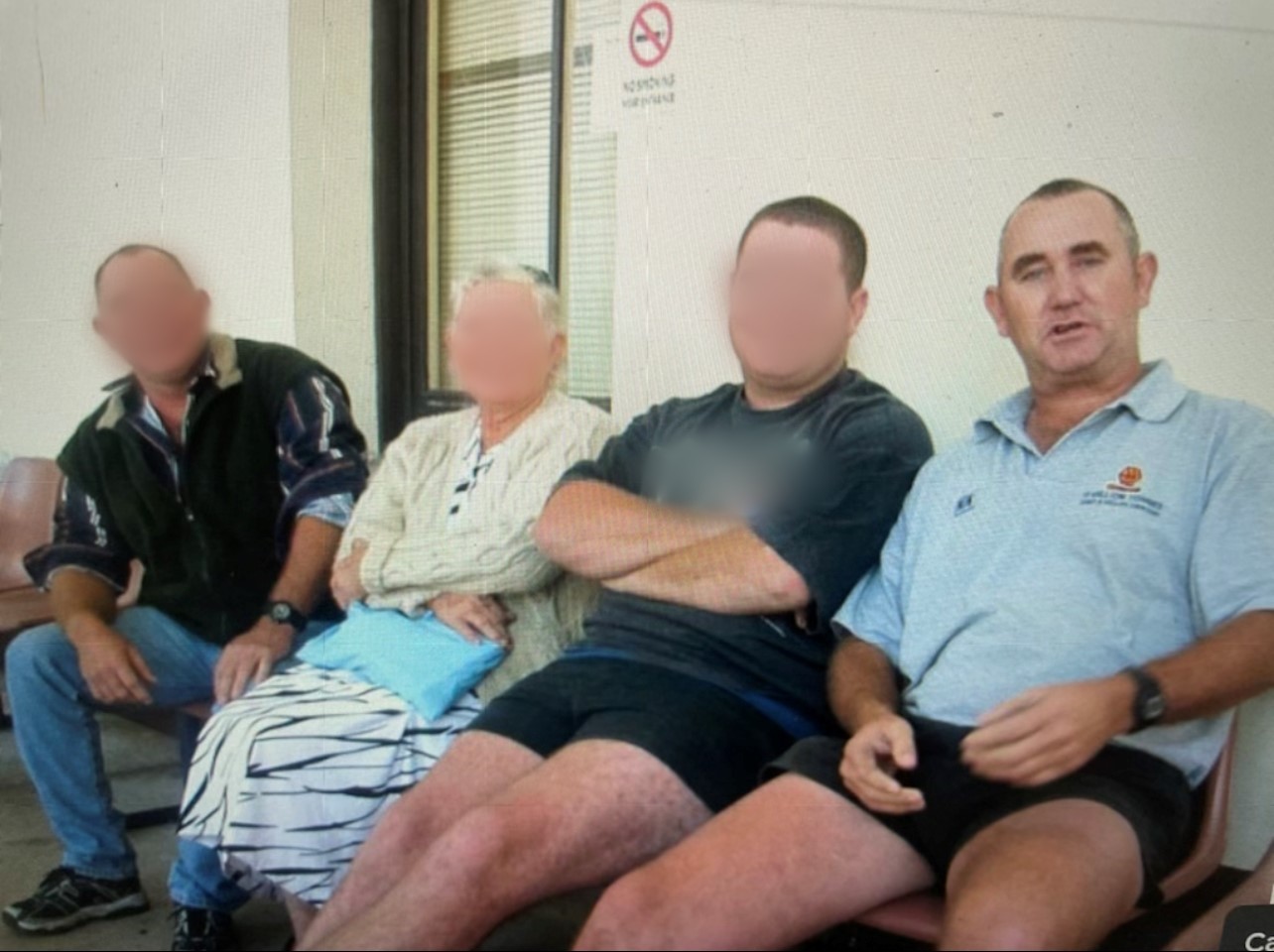 Four people sit in a row.  Three have their faces blurred.  The fourth is a man wearing a light blue polo shirt.