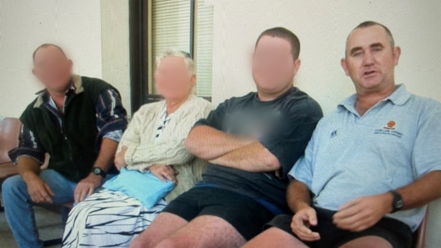Four people sit in a row. Three have their faces blurred. The fourth is a man wearing a light blue polo shirt.