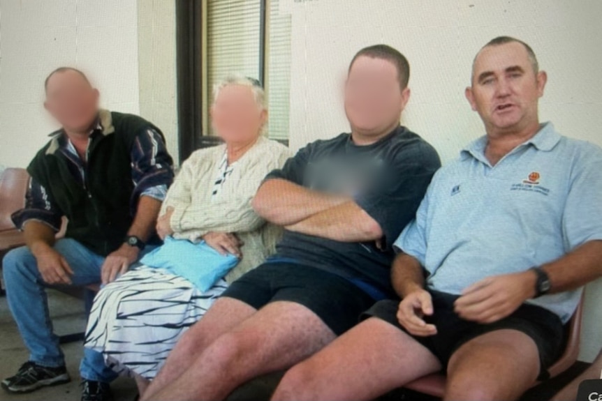 Four people sit in a row. Three have their faces blurred. The fourth is a man wearing a light blue polo shirt.