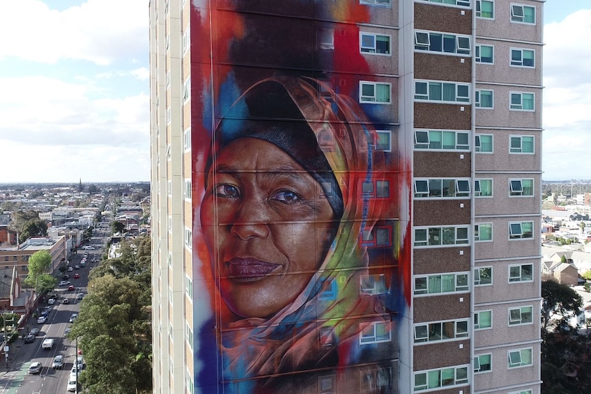 An aerial shot mid-way up the mural features the portrait of resident Badria Abdo.