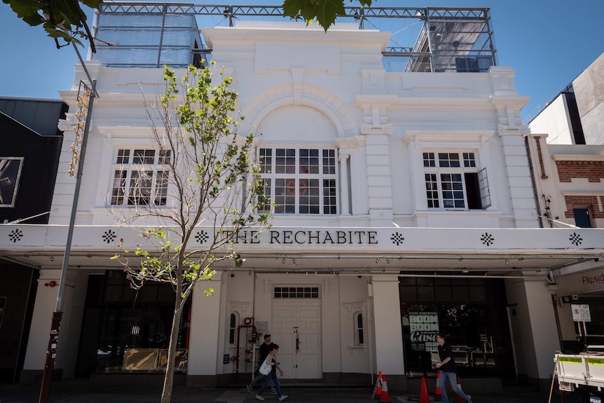 The Rechabite exterior - large white heritage building with people walking past.