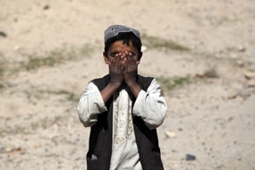 An Afghan boy covers his face as an U.S. Army convoy passes on March 5, 2010 near Sha-Wali-Kot in Kandahar province (Getty Im...
