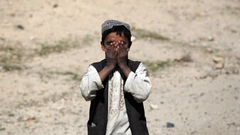 An Afghan boy covers his face as an U.S. Army convoy passes on March 5, 2010 near Sha-Wali-Kot in Kandahar province (Getty Im...