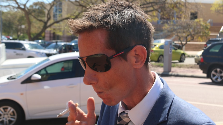 A side view of a man wearing sunglasses and a blue suit