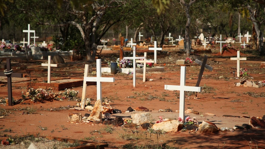 Crosses and flowers mark graves in the dirt at Broome cemetery.