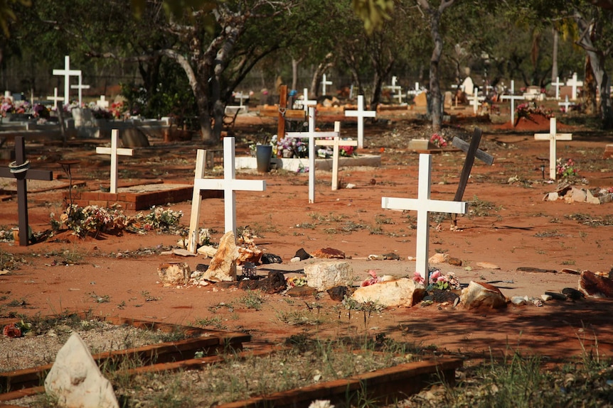 Crosses and flowers mark graves in the dirt at Broome cemetery.