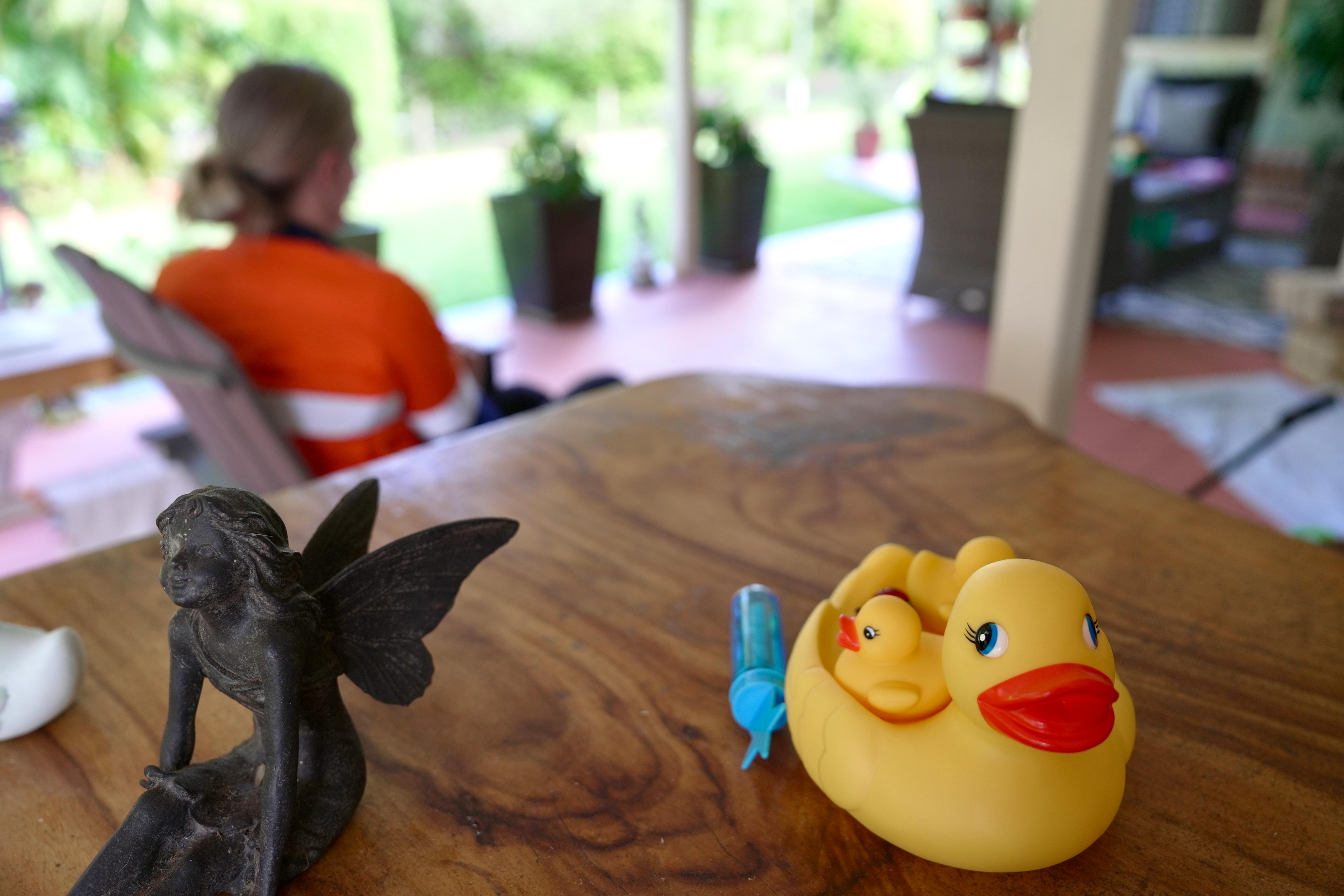 Una mujer borrosa en el fondo de una foto de un pato de goma.
