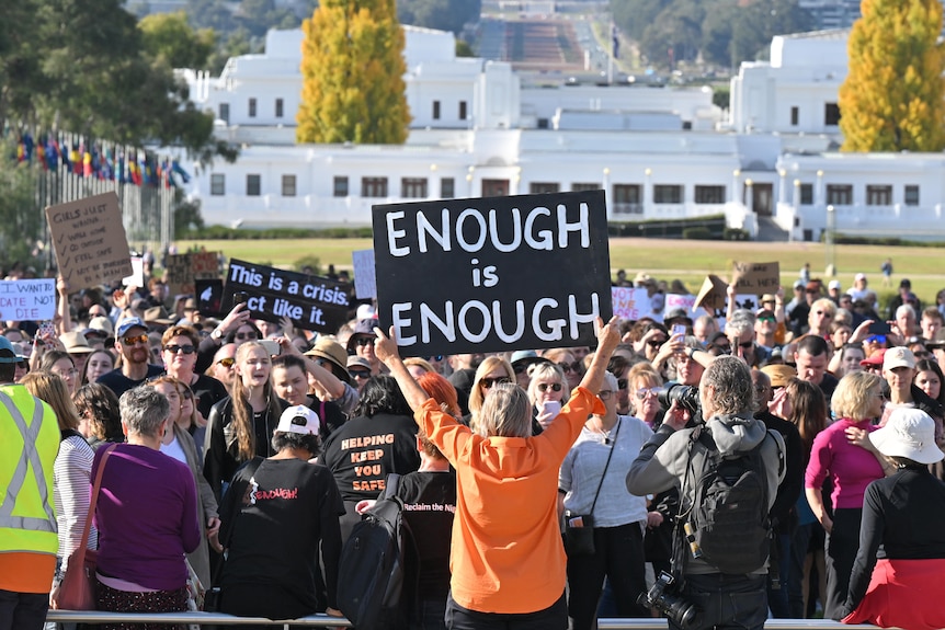 Protesters carry signs at a rally to a call for action to end violence against women.