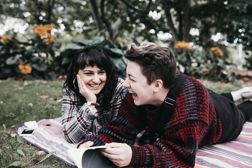 Couple on a picnic rug looking happy.