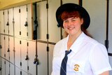 Indigenous student Greta Stephensen stand in front of a row of school lockers.