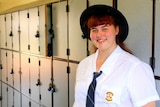 Indigenous student Greta Stephensen stand in front of a row of school lockers.