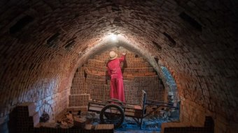 A woman removes bricks from inside an arched kiln in Cambodia