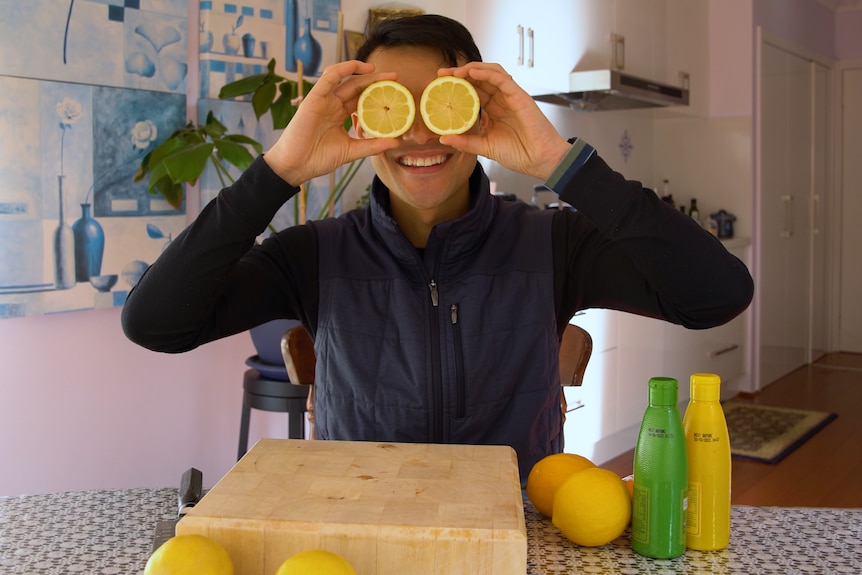 A photo of Thanh holding two pieces of lemon above his eyes