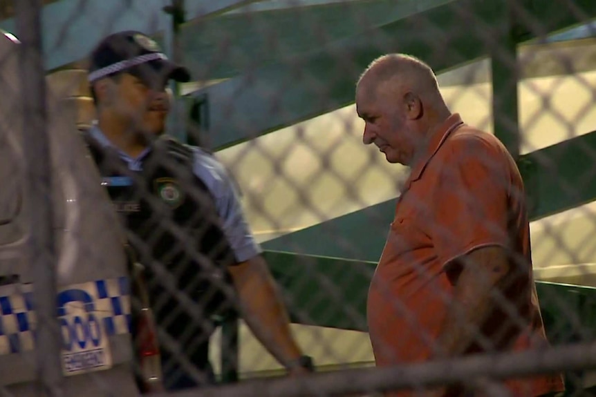 A man walks to a police car