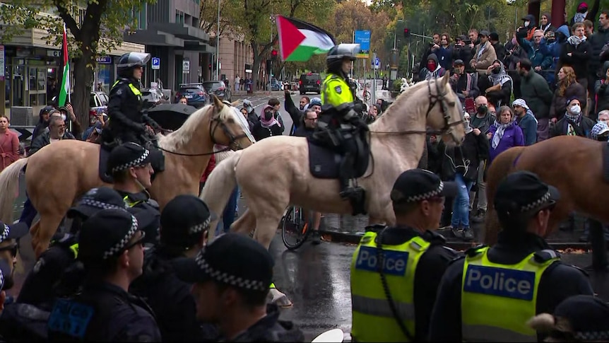 Mounted police officers on horses in the middle of a demonstration. 