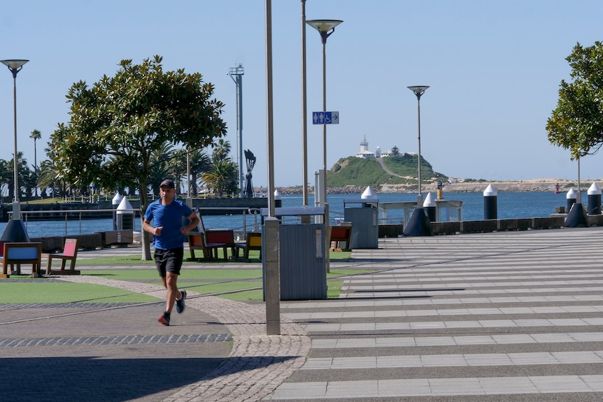 A man jogs along an empty foreshore