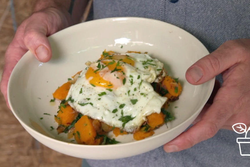 Bowl of fried pumpkin with 2 fried eggs on top.