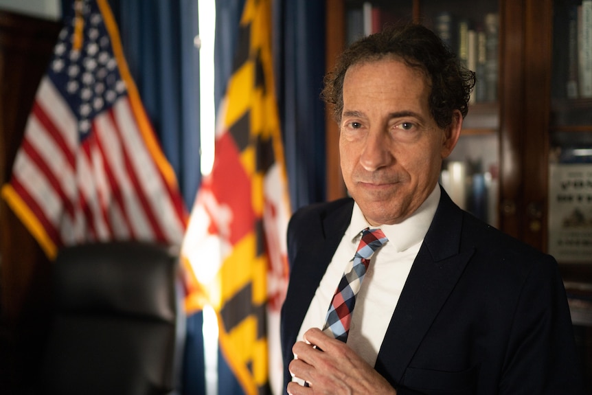 Jamie Raskin looks at camera in suit in front of US flag 