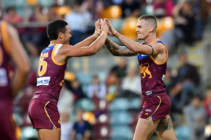 Dayne Beams (R) of the Lions celebrates kicking a goal with Cameron Rayner (L) against Hawthorn.