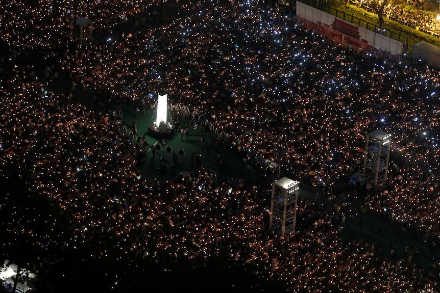 Thousands of people stand in a square holding lights as part of a vigil in Hong Kong