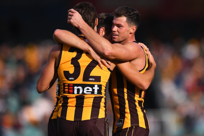 Three Hawthorn AFL players embrace after beating Adelaide Crows.