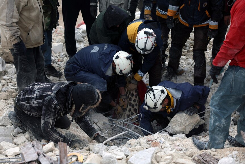 Civil defense workers search through the rubble of collapsed buildings in the Besnia village near the Turkish border.