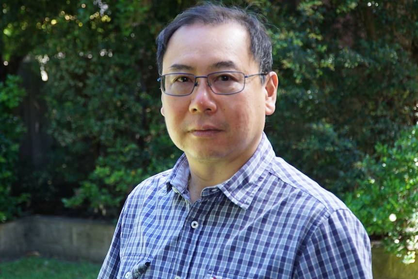 Francis Louie stands outside in a garden and looks at the camera.