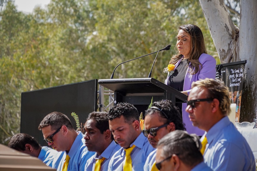 Jacinta price speaks into a microphone at a lectern. 
