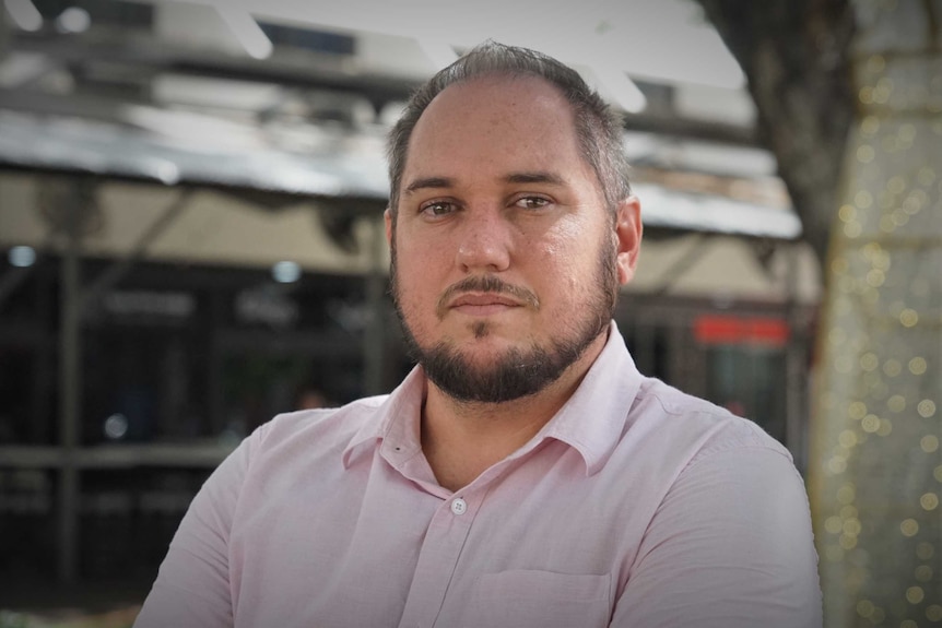 Peter Burnheim has his arms folded and looks seriously at the camera. He is standing in Darwin City.