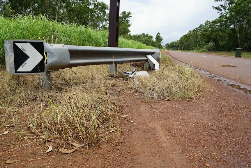 A skid mark on to dirt off a road with a downed sign.