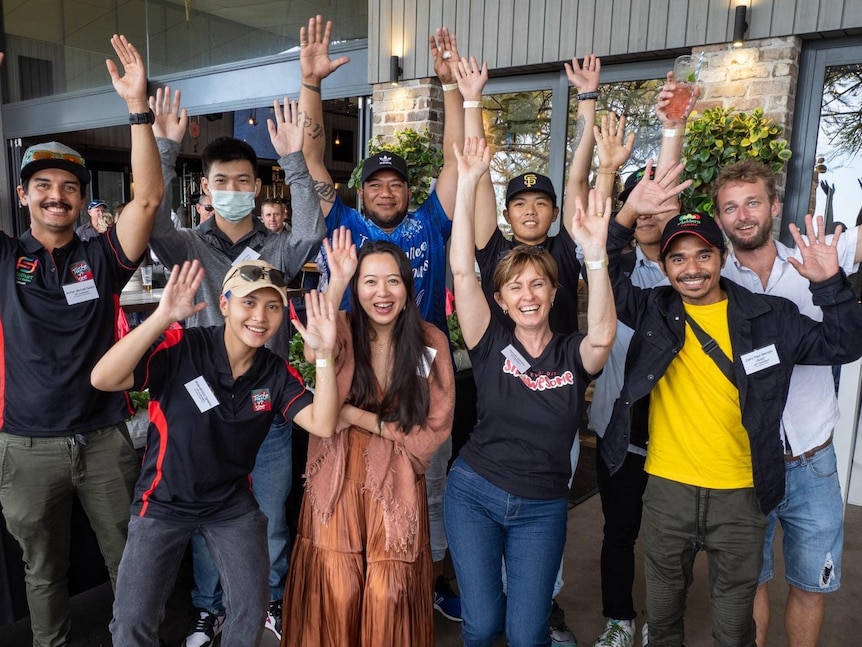 Ten people with their hands in the air.