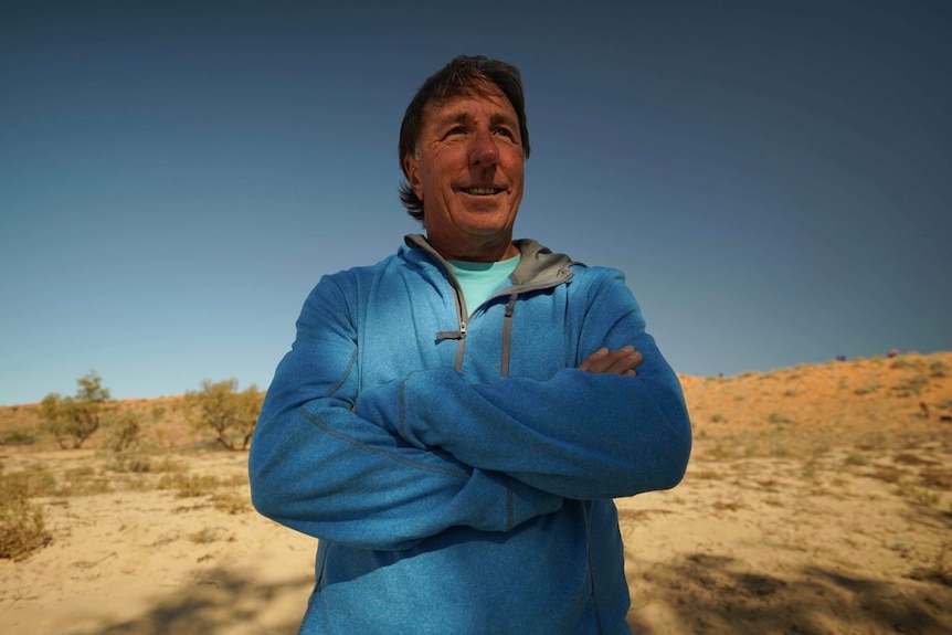  A man in a blue jumper at the bottom of a sand dune near Birdsville