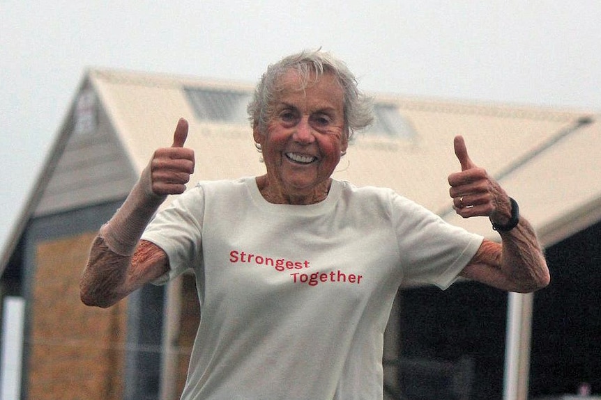 Judy Amoore Pollock gives two thumbs up while running in the rain.