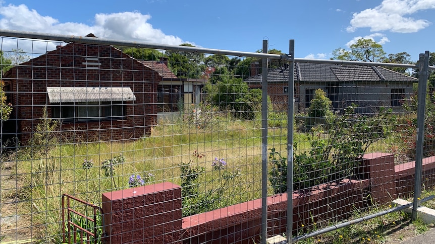 Two homes fenced off with broken windows, smashed doors and in a state of general vandalism