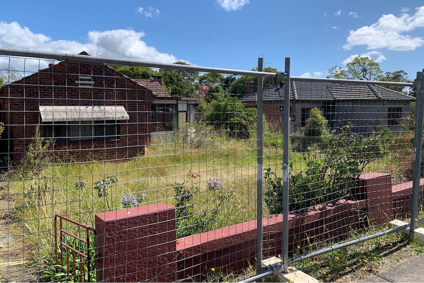 Two homes fenced off with broken windows, smashed doors and in a state of general vandalism