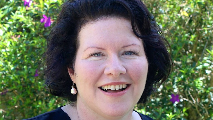 Kate Richards poses for photo in front of greenery.