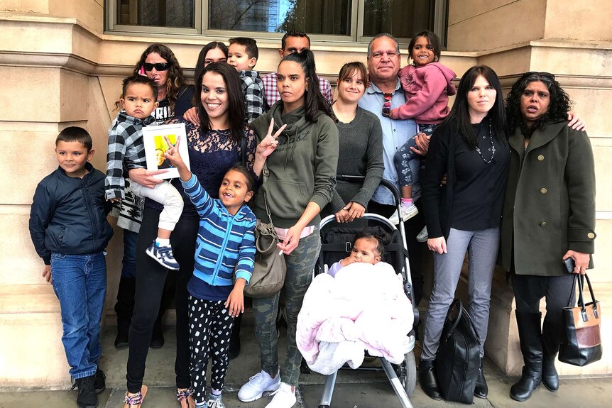 A group of people stands outside a courtroom.