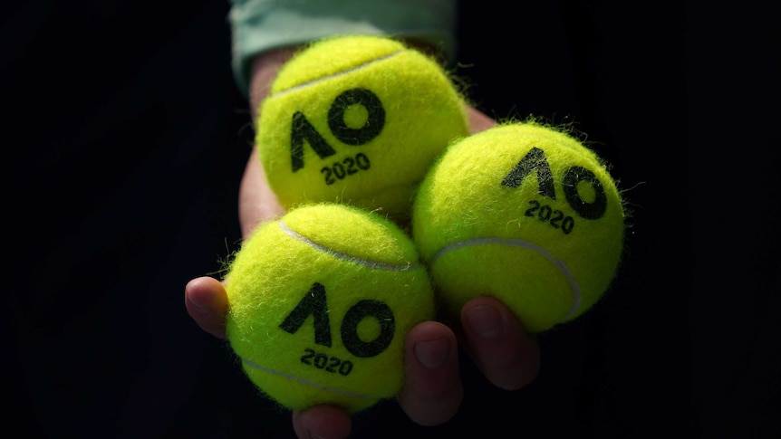 Close-up of a hand holding three Australian Open-branded tennis balls