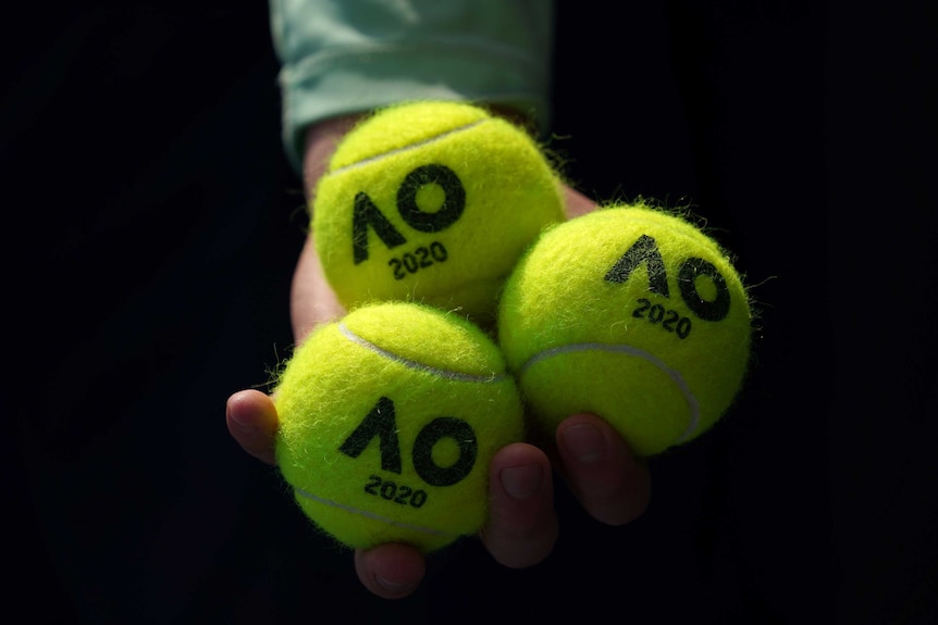 Close-up of a hand holding three Australian Open-branded tennis balls