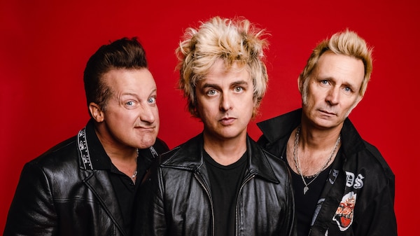 Three members of band Green Day wearing leather in a red photo studio
